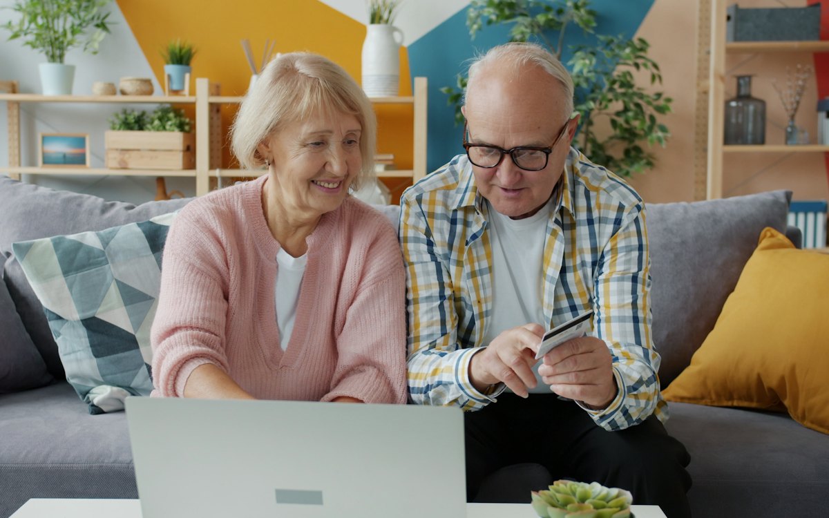 An older couple comparing details on a laptop at home