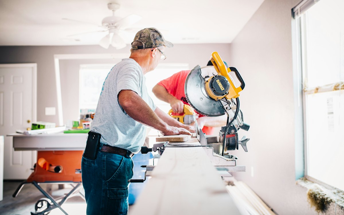 A man cutting lumber with a miter saw during a home project