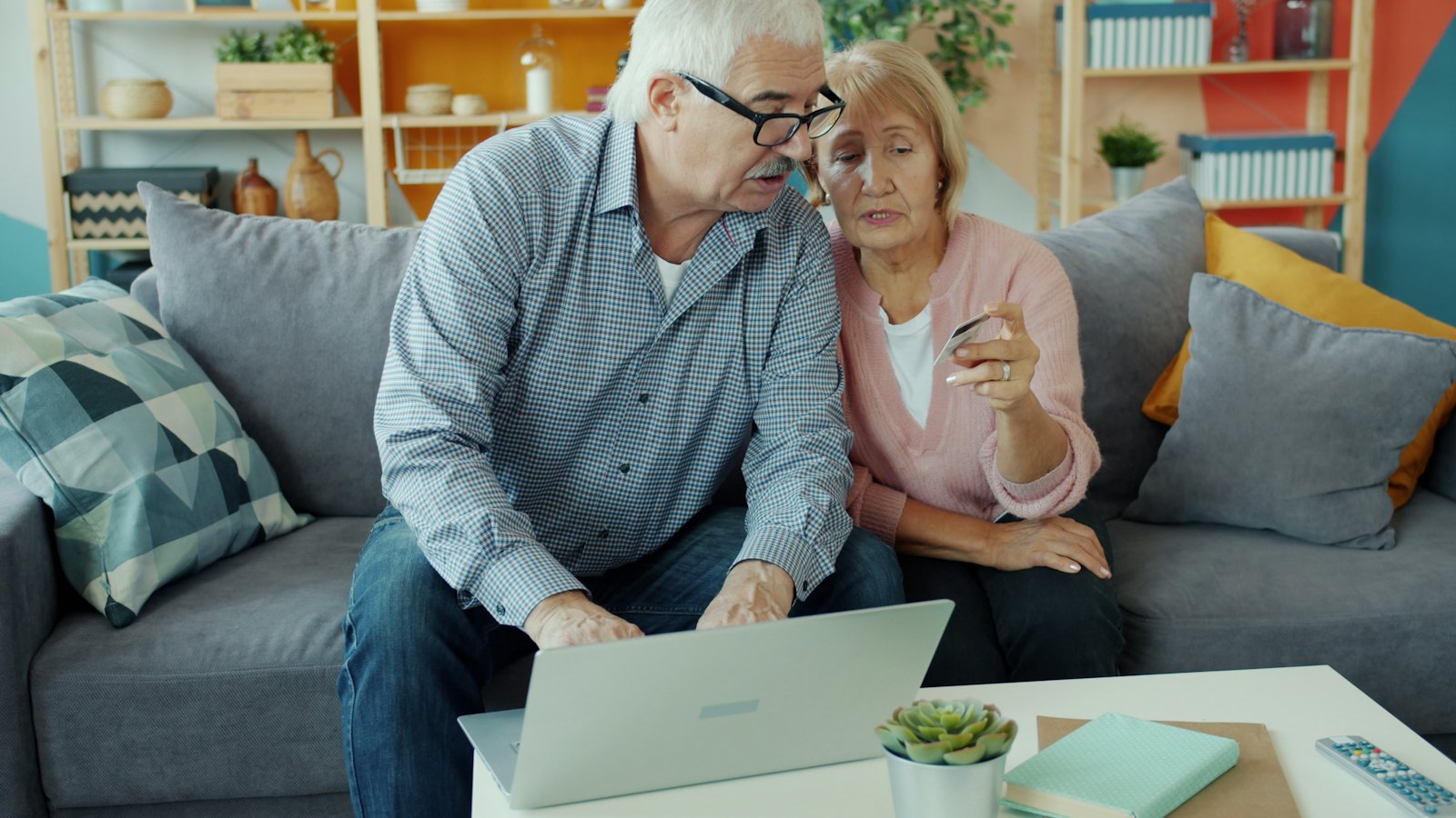 An older couple looking at a laptop together on their couch